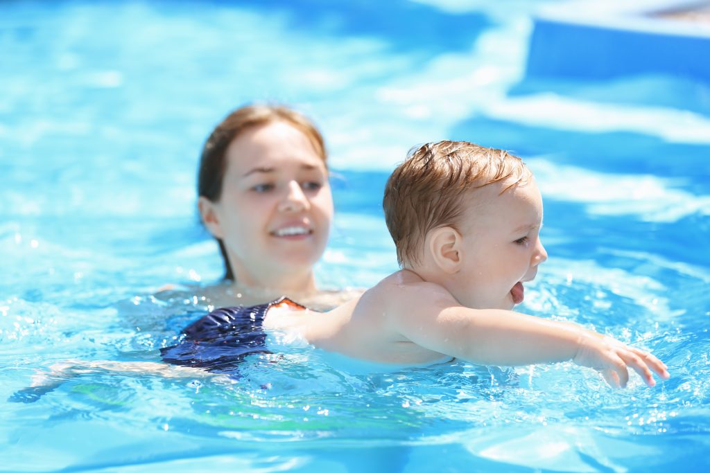 Child swimming lesson. Cute little boy learning to swim with mother in pool, swim drills 