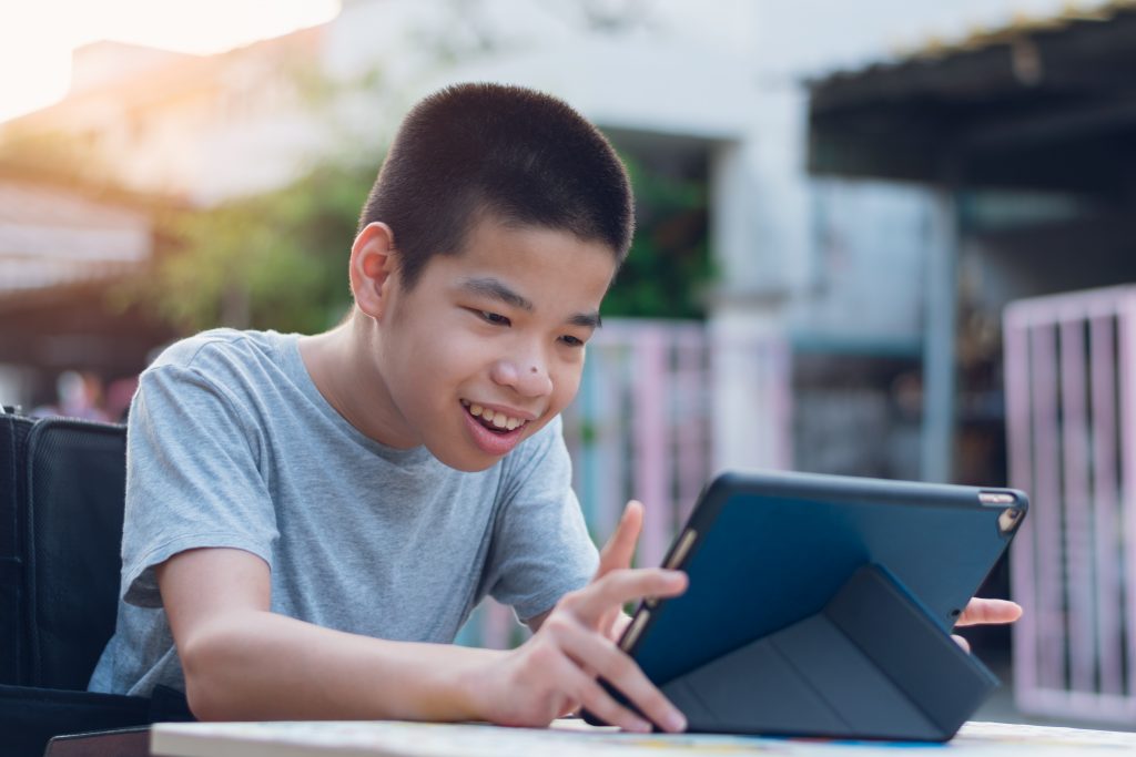 Disabled child on wheelchair happy time to use a tablet in the house with nature sun light, Special children's lifestyle, Life in the education age of special need kid, Happy disability boy 