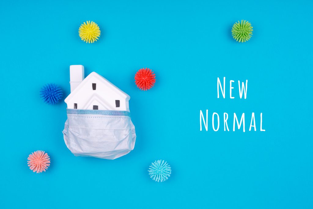 Cute little house covered with medicine mask and plastic balls as viruses on blue with New Normal wording. Coronavirus pandemic reduction, moving to new normal, economy reopening concept, public pools